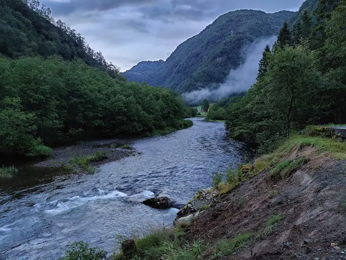 Elva gjennom dalen med tåke over fjellet
